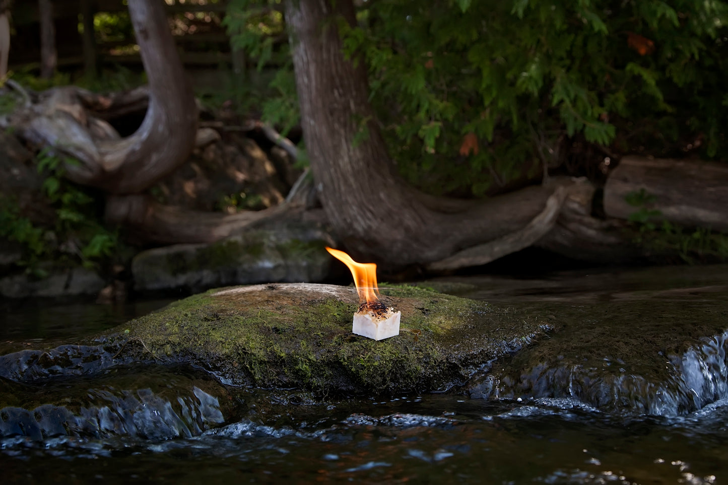 single burning cube on rock near a stream