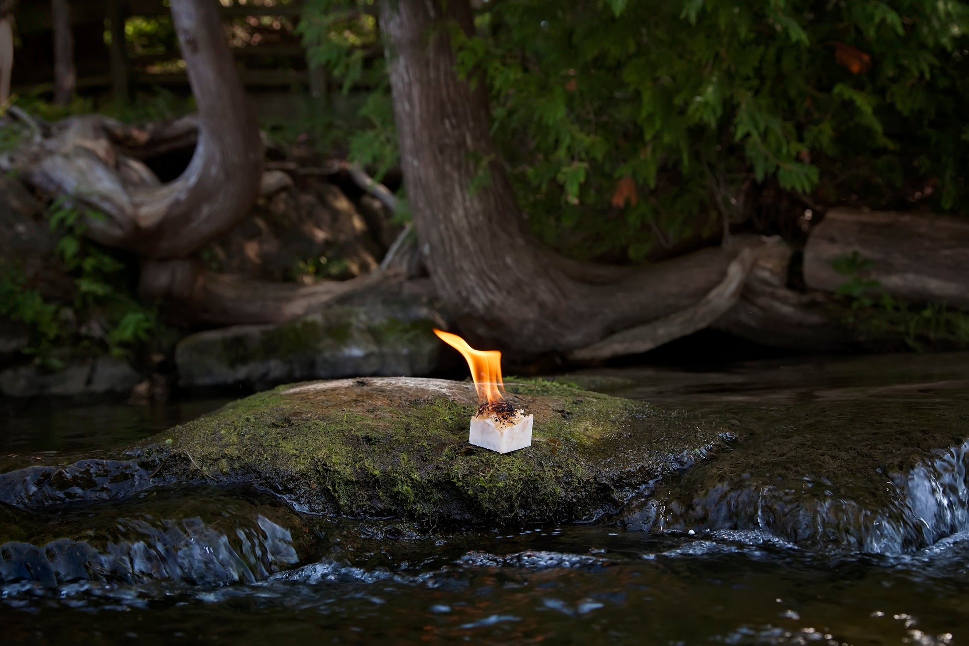 single burning cube on rock near a stream